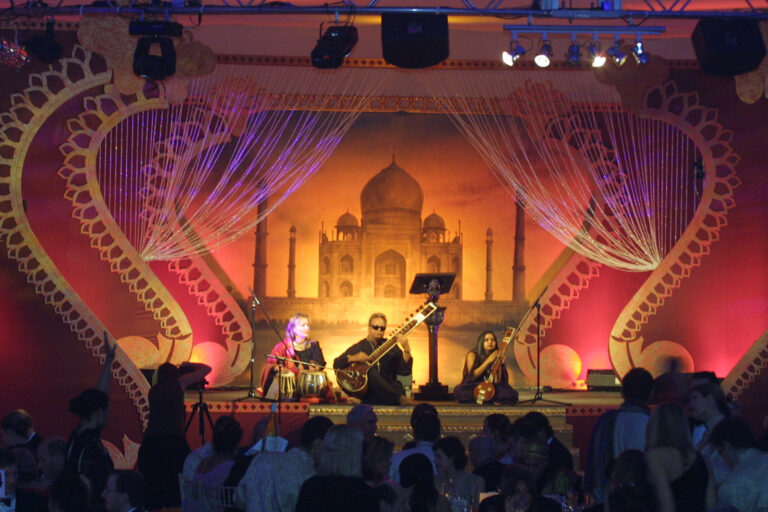 Indian musicians on stage with Taj Mahal backdop for British Red Cross London Ball